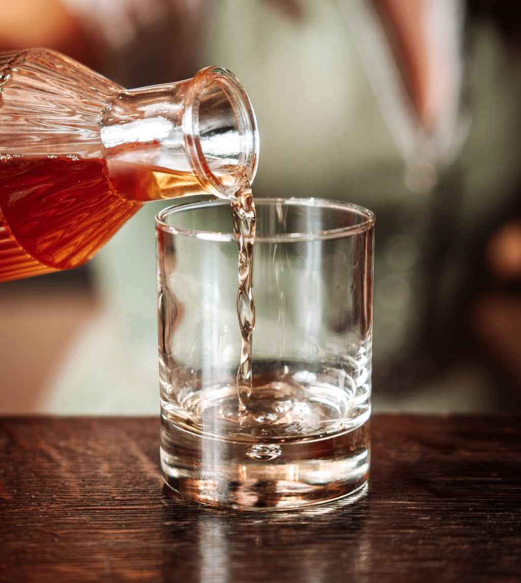 ee wird aus einer stilvollen Glaskaraffe in ein Trinkglas gegossen