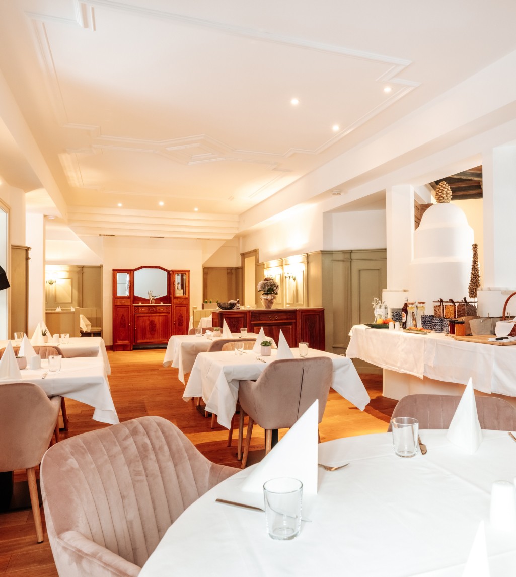 Restaurant im Boutiquehotel Hubertus mit weiß gedeckten Tischen und stilvoller Inneneinrichtung.